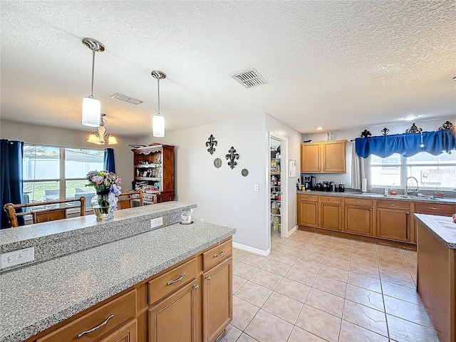 kitchen featuring a wealth of natural light, light tile patterned floors, hanging light fixtures, and a textured ceiling