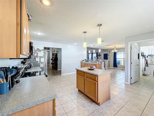 kitchen with light tile patterned floors, a center island, a textured ceiling, and hanging light fixtures