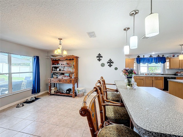 kitchen featuring a chandelier, black dishwasher, a wealth of natural light, and light tile patterned flooring