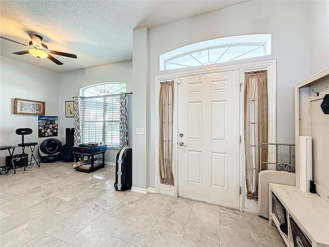 foyer featuring ceiling fan and a textured ceiling