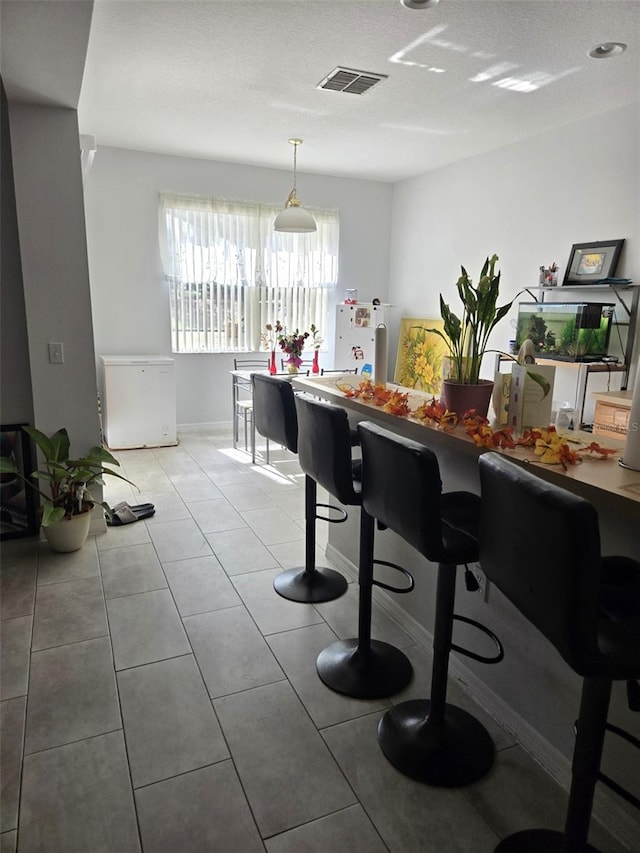 tiled dining area with a textured ceiling