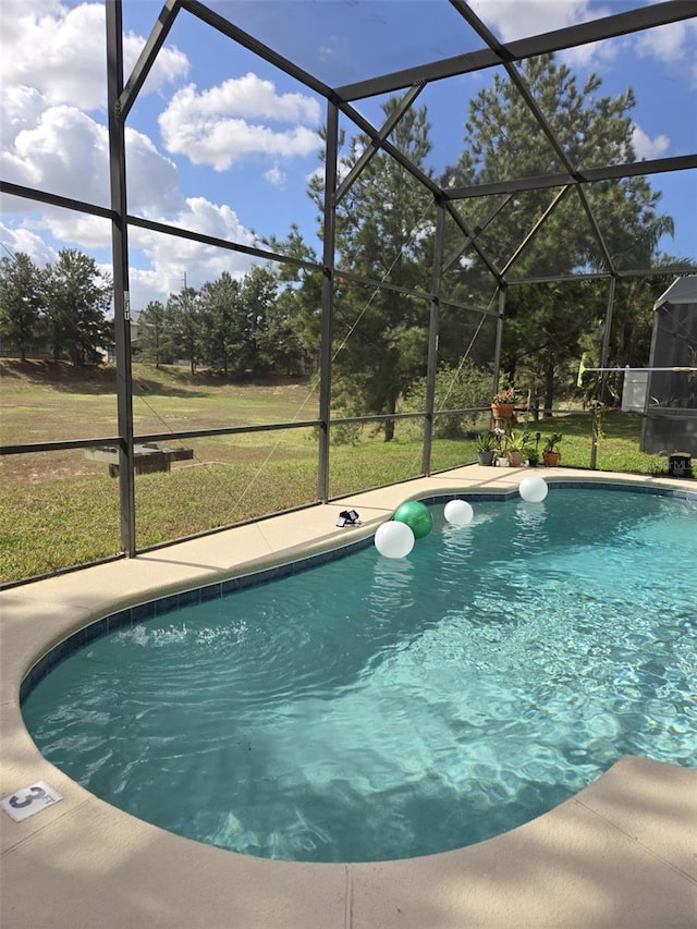 view of pool featuring glass enclosure and a lawn