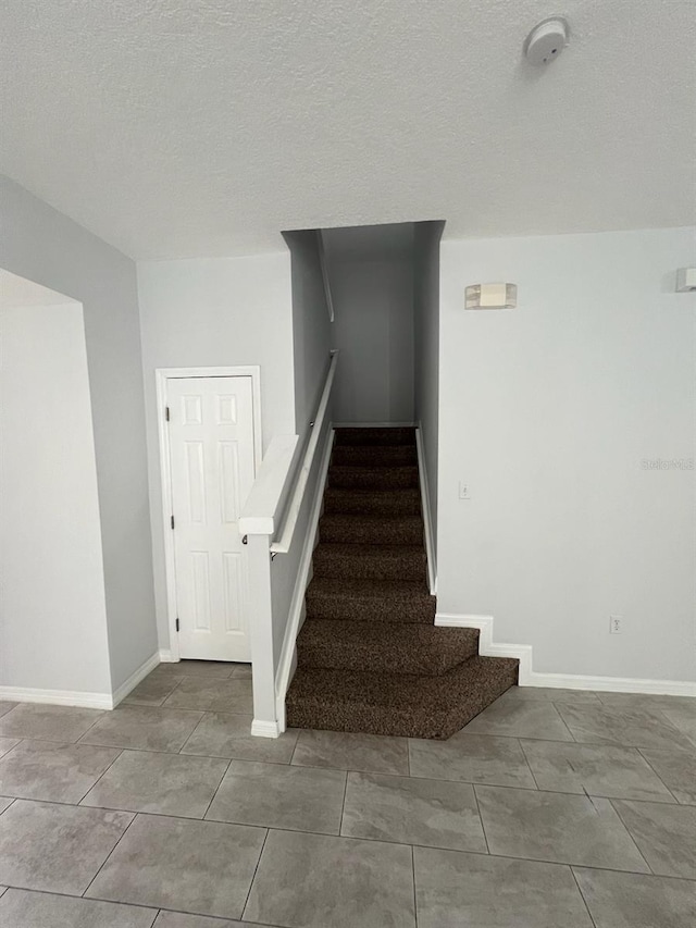 staircase featuring a textured ceiling