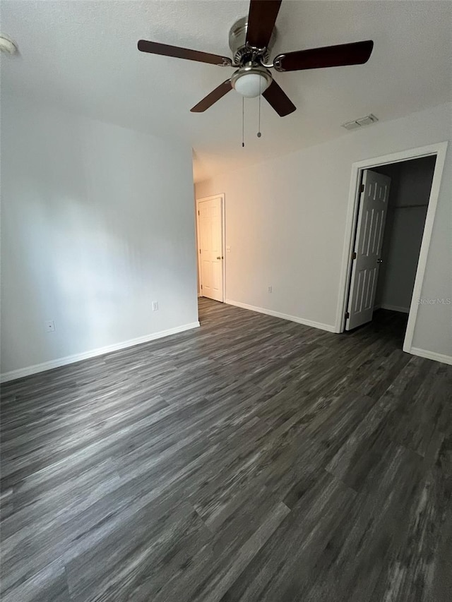 empty room with ceiling fan and dark wood-type flooring