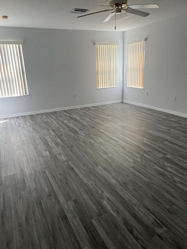 spare room featuring a textured ceiling, a wealth of natural light, ceiling fan, and dark hardwood / wood-style floors