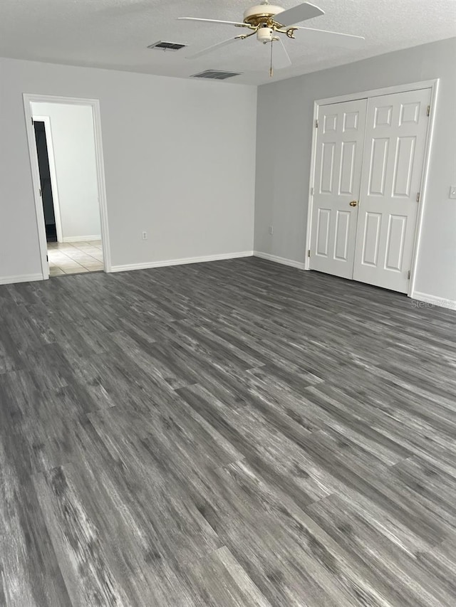 spare room featuring a textured ceiling, ceiling fan, and dark wood-type flooring