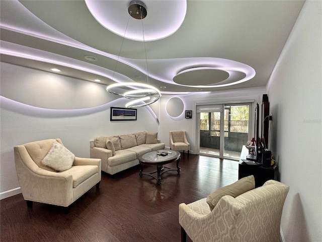 living room with a raised ceiling and dark wood-type flooring