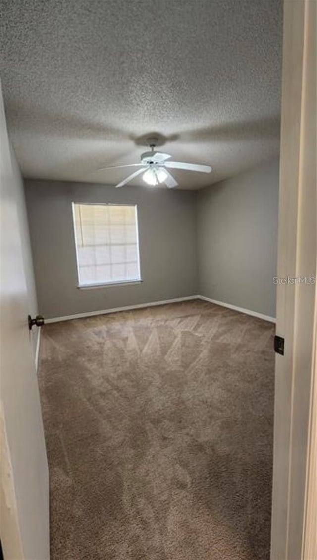 carpeted spare room featuring a textured ceiling and ceiling fan