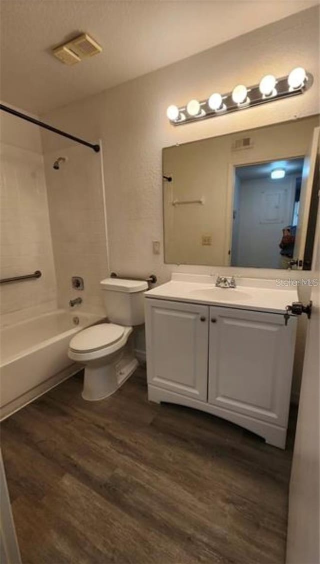 full bathroom featuring hardwood / wood-style flooring, vanity, toilet, and tiled shower / bath