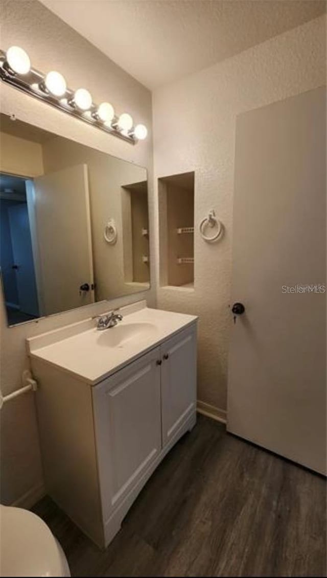 bathroom with hardwood / wood-style flooring, vanity, and toilet