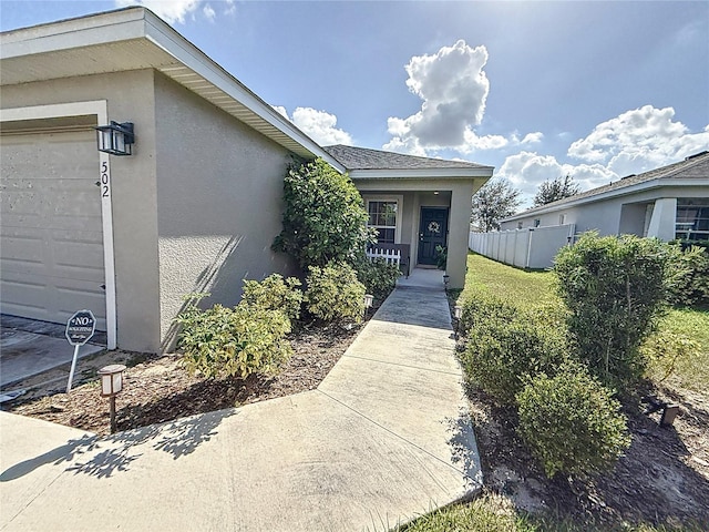 502 Pentas Ln, Haines City, FL 33844 - doorway to property featuring stucco siding, an attached garage, and fence