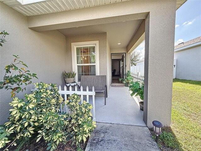 502 Pentas Ln, Haines City, FL 33844 - view of exterior entry featuring stucco siding, fence, and a patio area