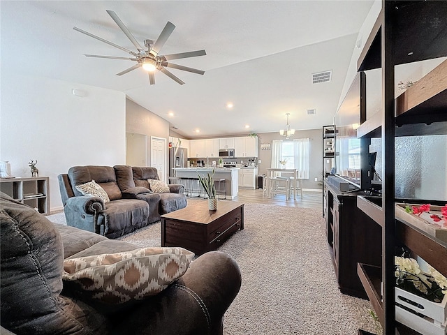 carpeted living room featuring ceiling fan with notable chandelier and vaulted ceiling