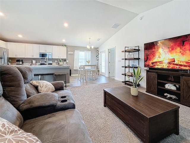 living room featuring a chandelier, light carpet, and vaulted ceiling