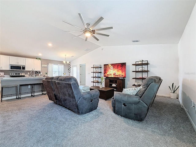 carpeted living room with ceiling fan with notable chandelier, sink, and vaulted ceiling