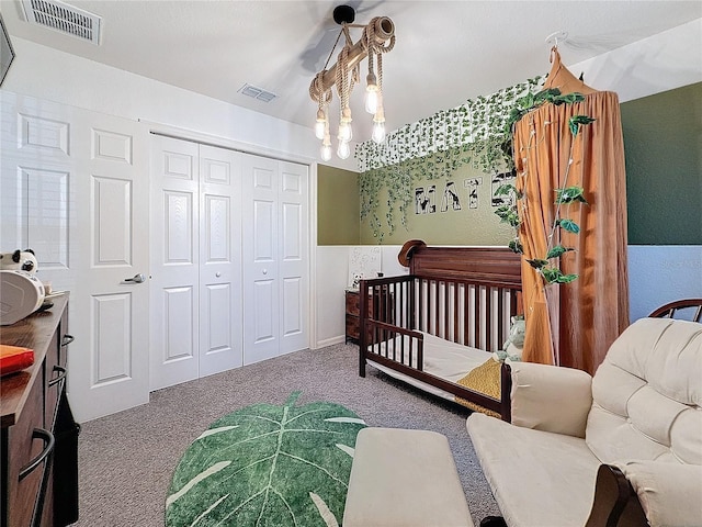 bedroom with a notable chandelier, a crib, carpet floors, and a closet