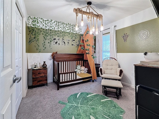 bedroom with carpet, a closet, an inviting chandelier, and a nursery area