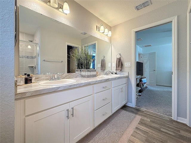 bathroom featuring hardwood / wood-style flooring, vanity, a shower with shower door, and a textured ceiling