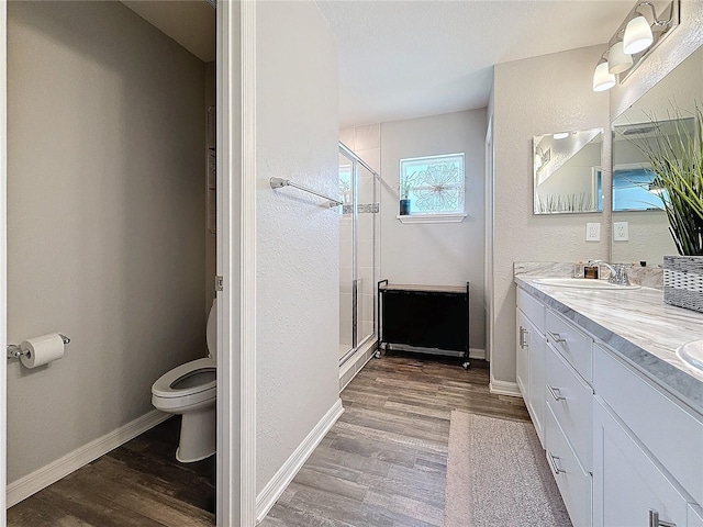 bathroom featuring an enclosed shower, vanity, toilet, and wood-type flooring