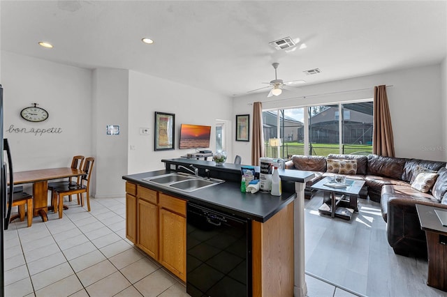 kitchen featuring ceiling fan, sink, a center island with sink, dishwasher, and stainless steel refrigerator