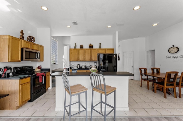 kitchen with a kitchen bar, a center island, black appliances, and light hardwood / wood-style floors