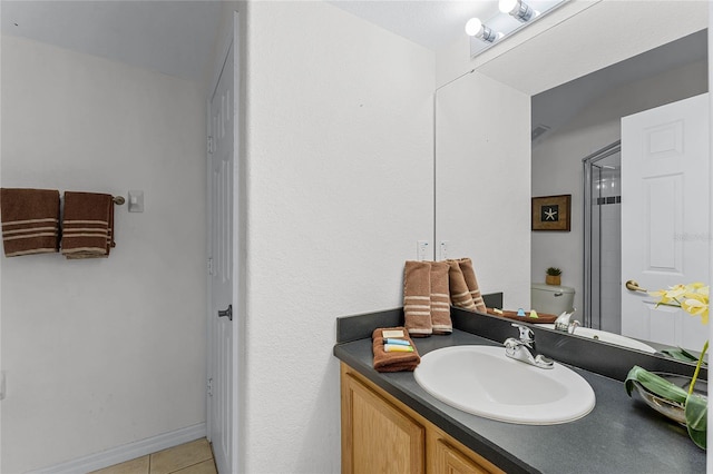 bathroom featuring tile patterned flooring, vanity, a shower with door, and toilet