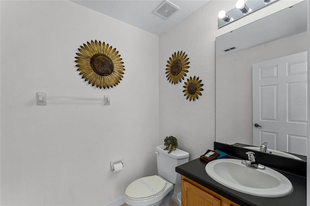 bathroom with vanity, a textured ceiling, and toilet