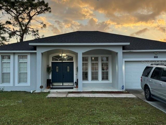 exterior entry at dusk with a lawn and a garage