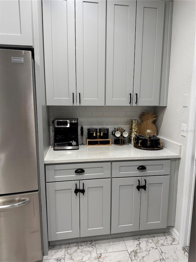 kitchen with decorative backsplash, stainless steel refrigerator, and gray cabinets