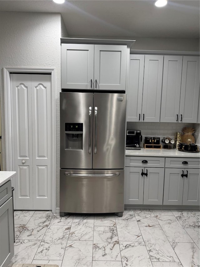 kitchen with tasteful backsplash, gray cabinets, and stainless steel fridge