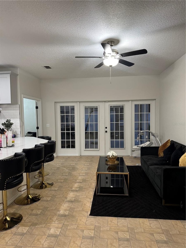 living room with ceiling fan and a textured ceiling