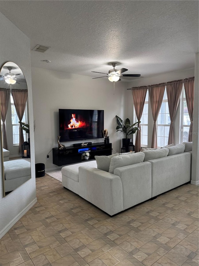 living room with a wealth of natural light, ceiling fan, and a textured ceiling