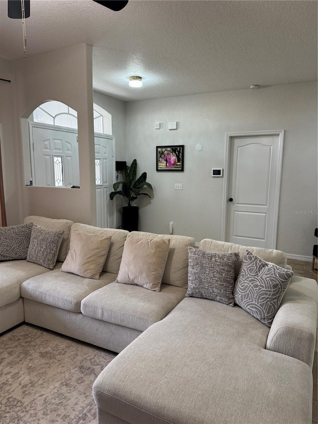 carpeted living room with ceiling fan and a textured ceiling