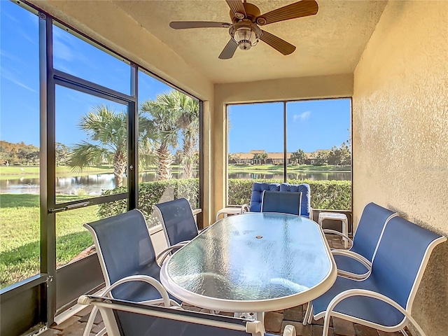 sunroom with ceiling fan, a healthy amount of sunlight, and a water view