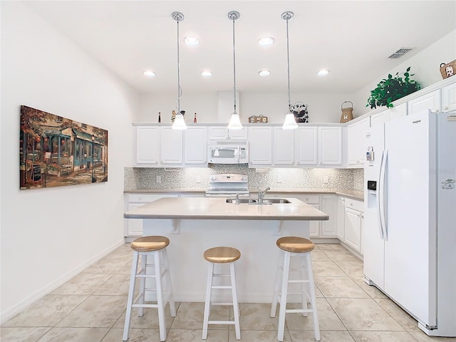 kitchen featuring a kitchen island with sink, white cabinets, hanging light fixtures, and white appliances