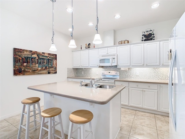 kitchen featuring a breakfast bar, pendant lighting, white appliances, and white cabinetry