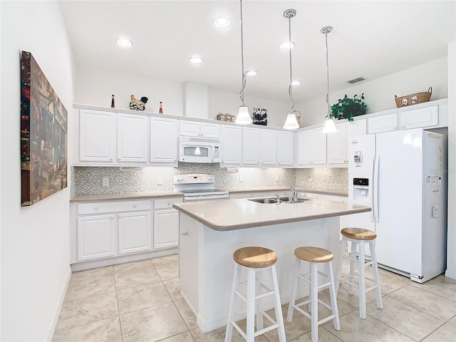 kitchen featuring white cabinetry, white appliances, a kitchen island with sink, and hanging light fixtures