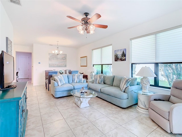 tiled living room with ceiling fan with notable chandelier and a wealth of natural light