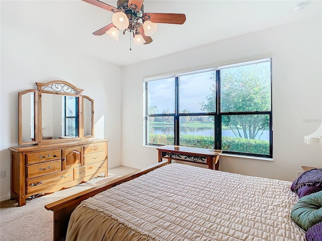 carpeted bedroom featuring a water view and ceiling fan