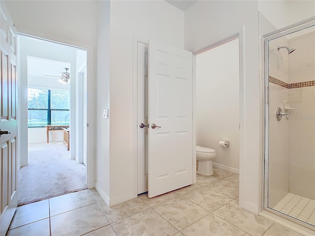 bathroom featuring tile patterned floors, ceiling fan, a shower with door, and toilet