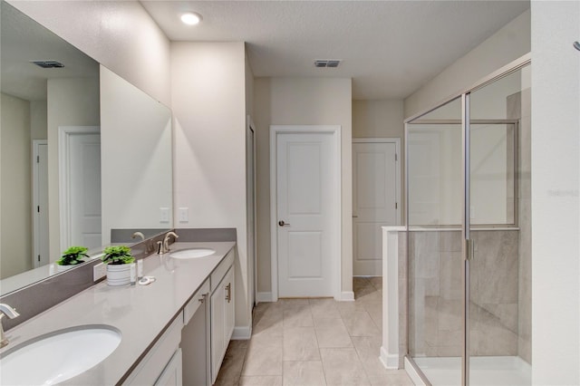 bathroom featuring vanity, a textured ceiling, and a shower with door