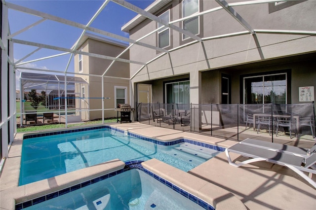 view of pool featuring an in ground hot tub, a patio, glass enclosure, and grilling area