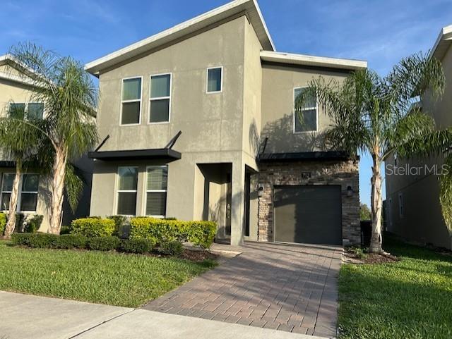 712 Whistling Straits Blvd, Davenport, FL 33896 - view of front facade featuring stucco siding, decorative driveway, a garage, and a front yard