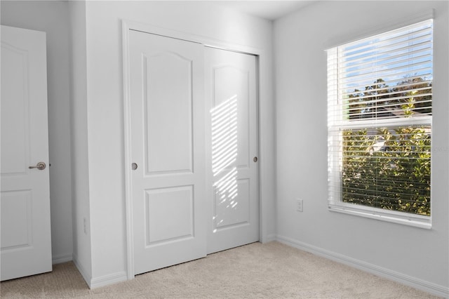 unfurnished bedroom featuring a closet and light carpet