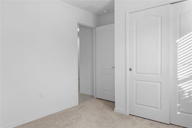 unfurnished bedroom featuring light colored carpet and a closet