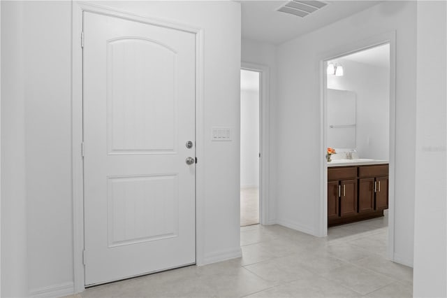 hall featuring sink and light tile patterned floors