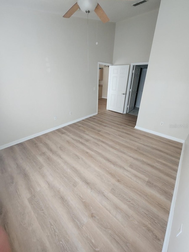 empty room featuring ceiling fan, high vaulted ceiling, and light hardwood / wood-style flooring