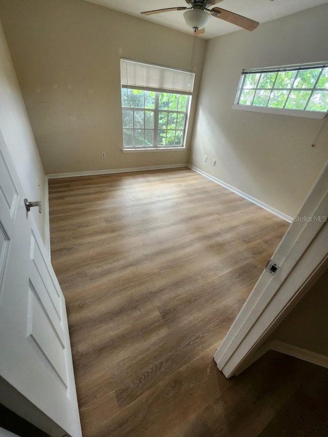 empty room with hardwood / wood-style floors, ceiling fan, and a healthy amount of sunlight