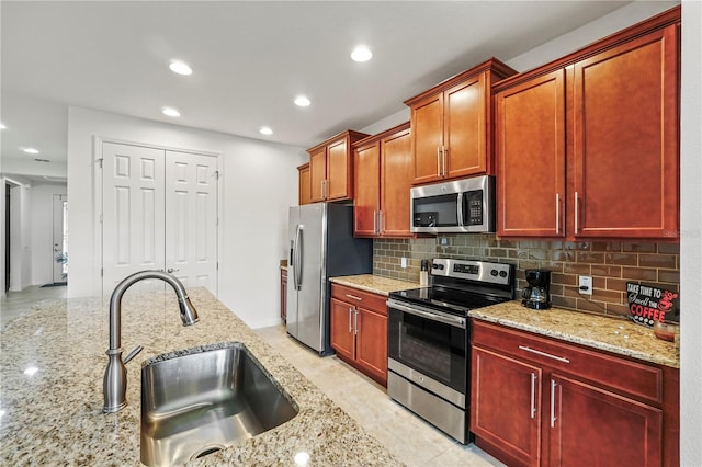 kitchen with tasteful backsplash, light stone countertops, sink, and stainless steel appliances