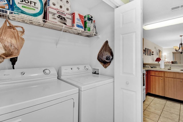 2216 Mystic Ring Loop, Poinciana, FL 34759 - laundry room featuring washing machine and clothes dryer, light tile patterned floors, and a chandelier